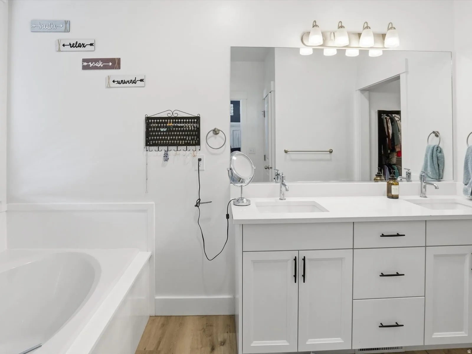 Bathroom featuring double vanity, light wood-style flooring, and a garden tub