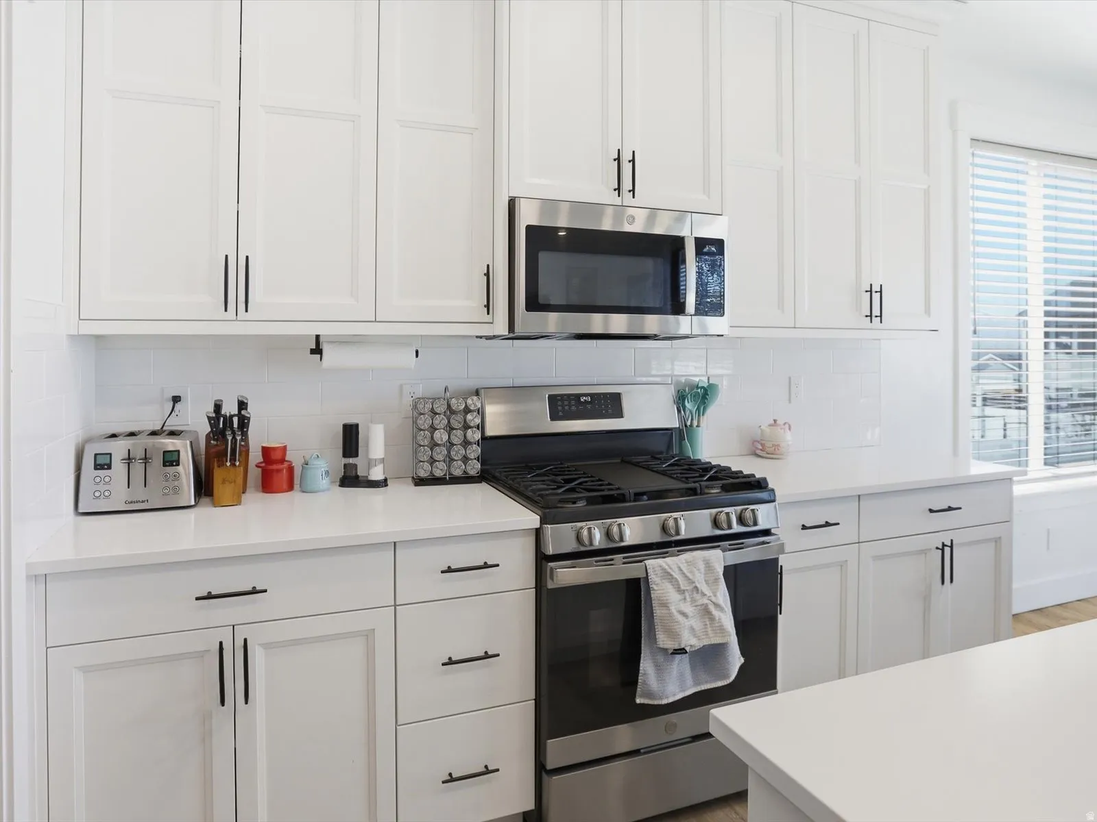 Kitchen with stainless steel appliances, white cabinetry, and tasteful backsplash