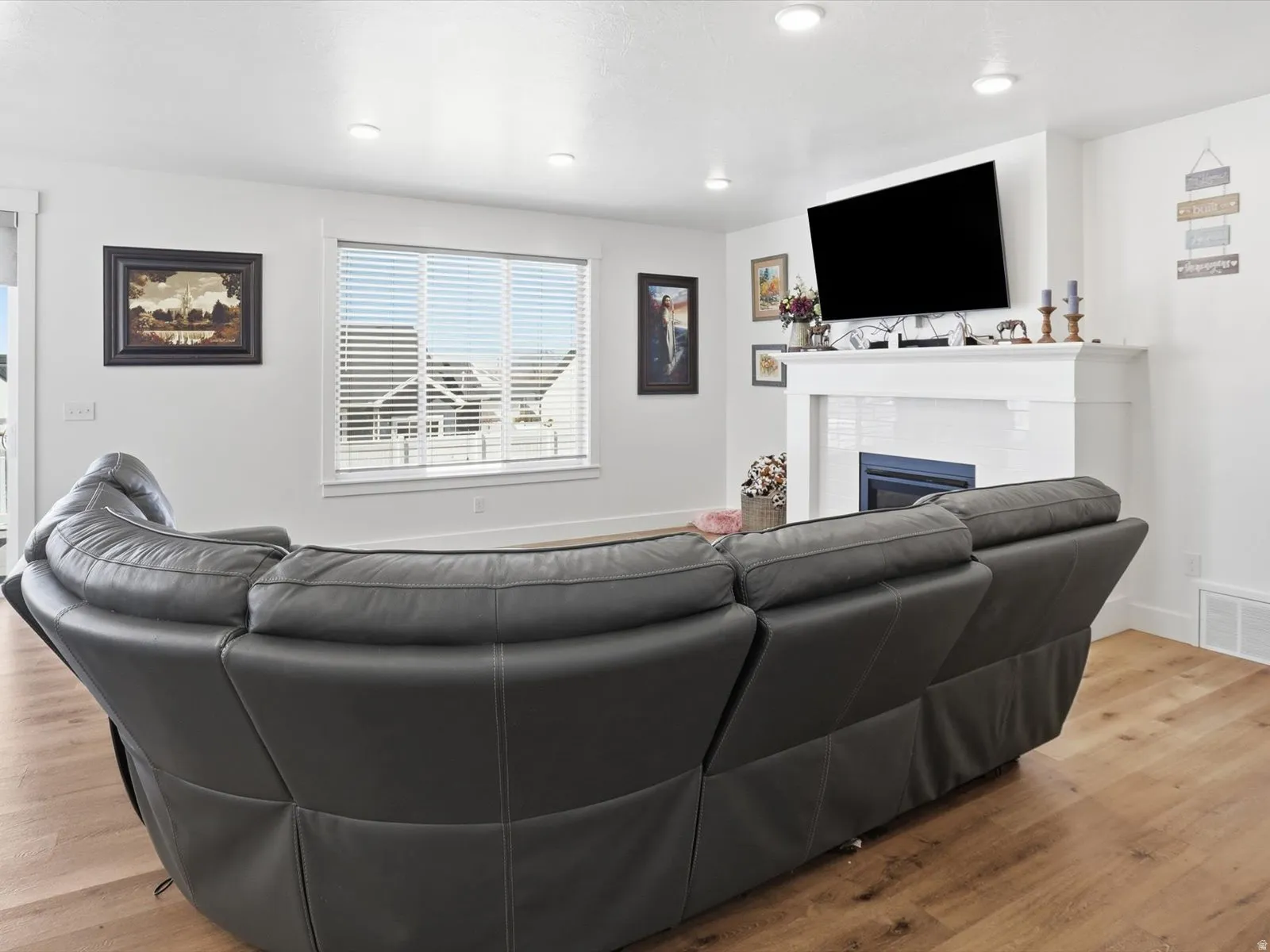 Living area with light wood-type flooring, a glass covered fireplace, and recessed lighting