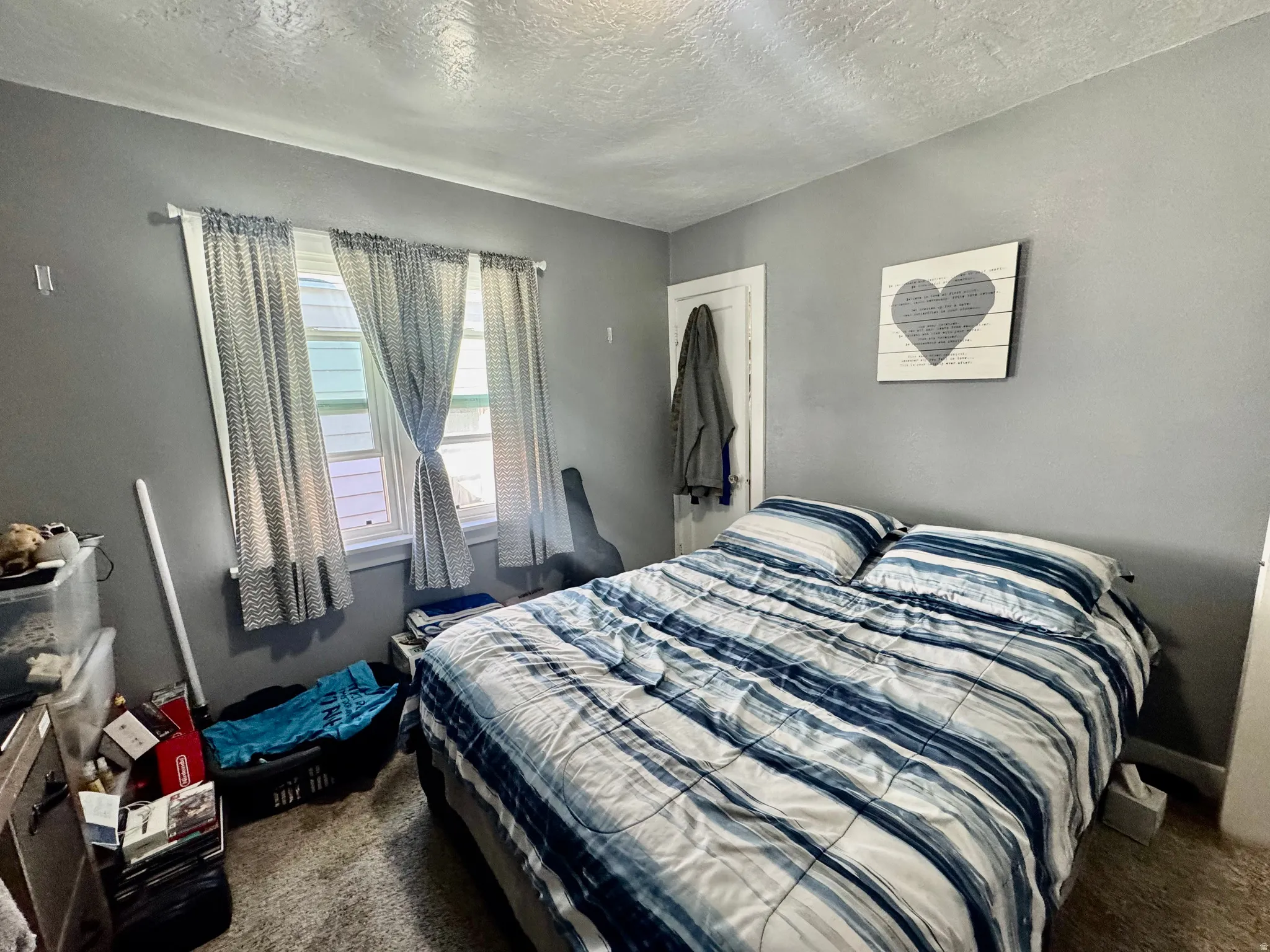 Bedroom with dark carpet and a textured ceiling