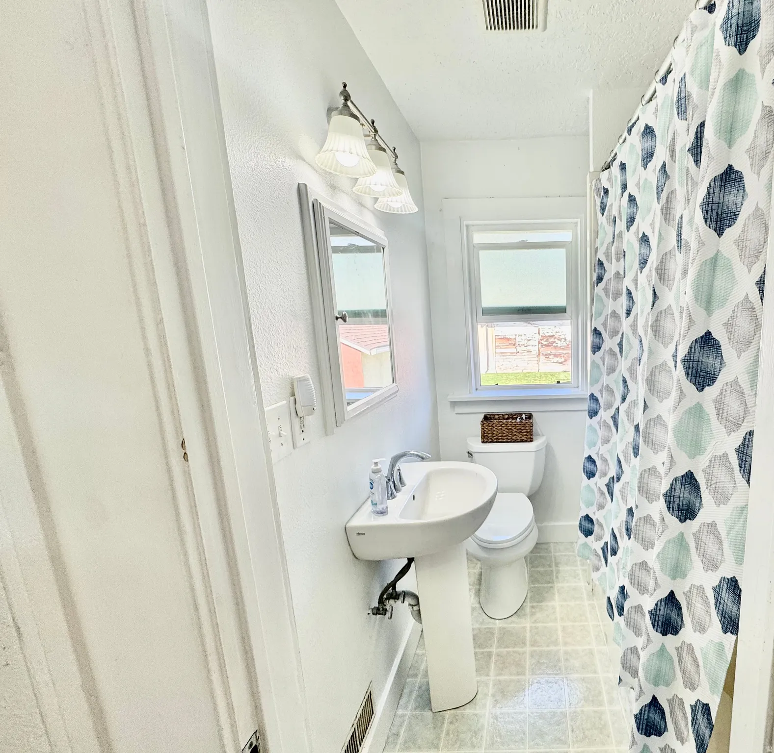Bathroom with curtained shower, a textured ceiling, and light tile patterned flooring