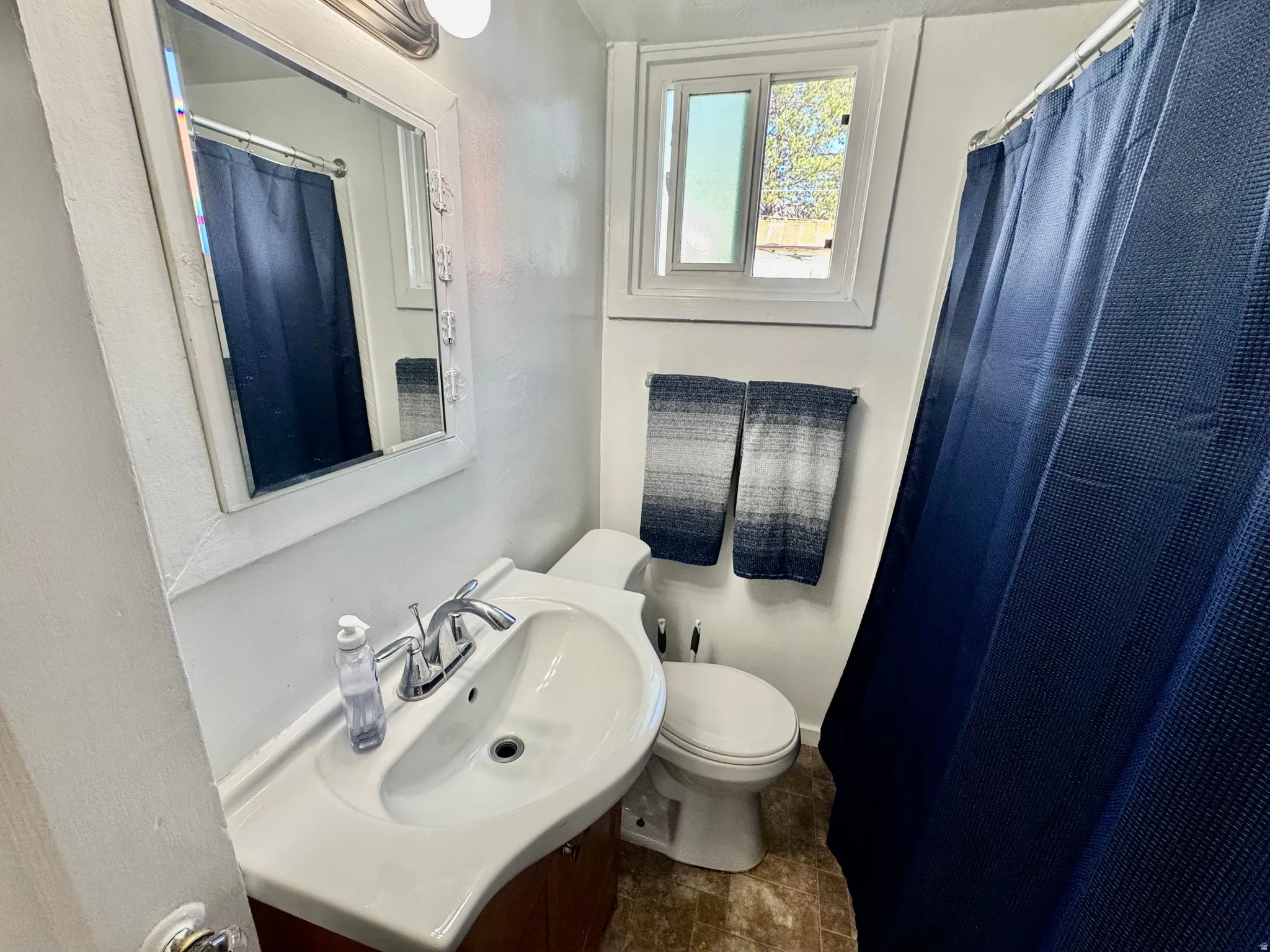 Full bath featuring vanity, a shower with shower curtain, and stone finish floors