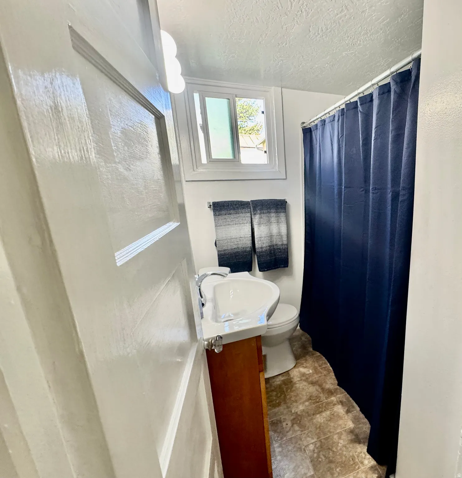 Full bathroom with vanity, a textured ceiling, a shower with shower curtain, and stone finish floors