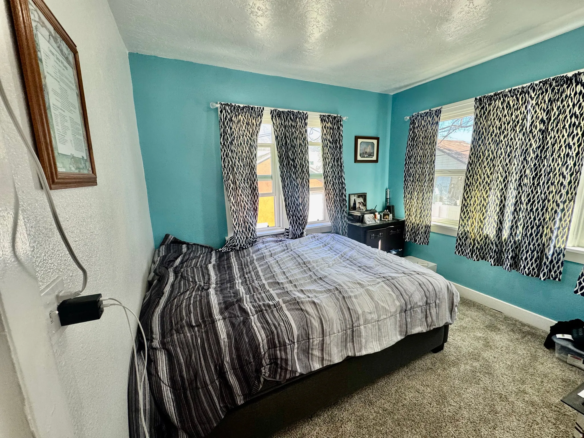 Bedroom with a textured ceiling, dark carpet, and a textured wall