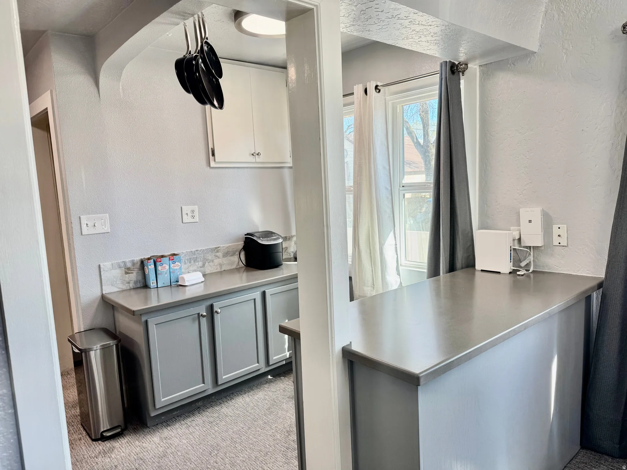 Kitchen featuring a textured wall, stainless steel counters, light carpet, and dual tone cabinets