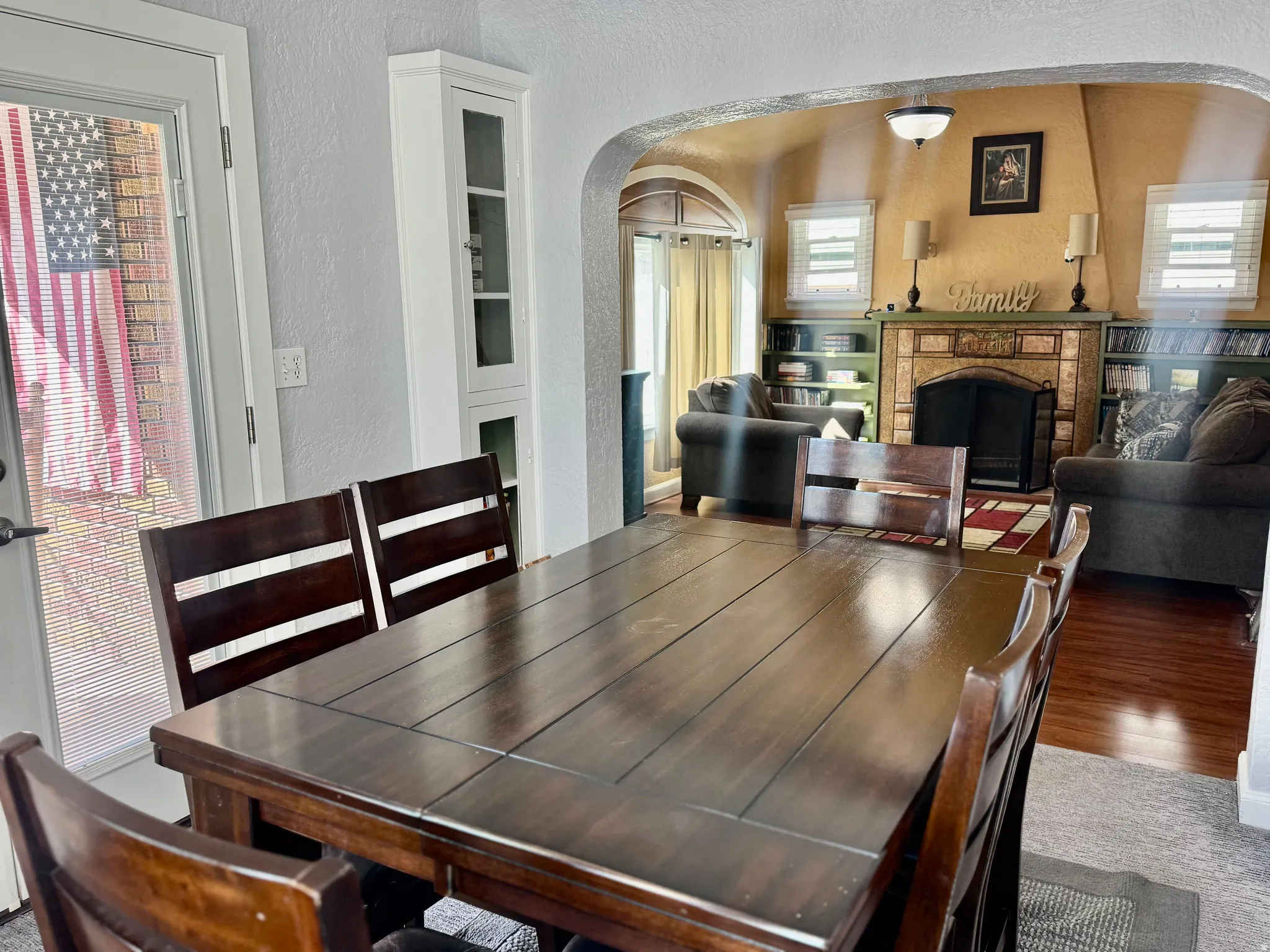 Carpeted dining area featuring a textured wall, arched walkways, and a fireplace