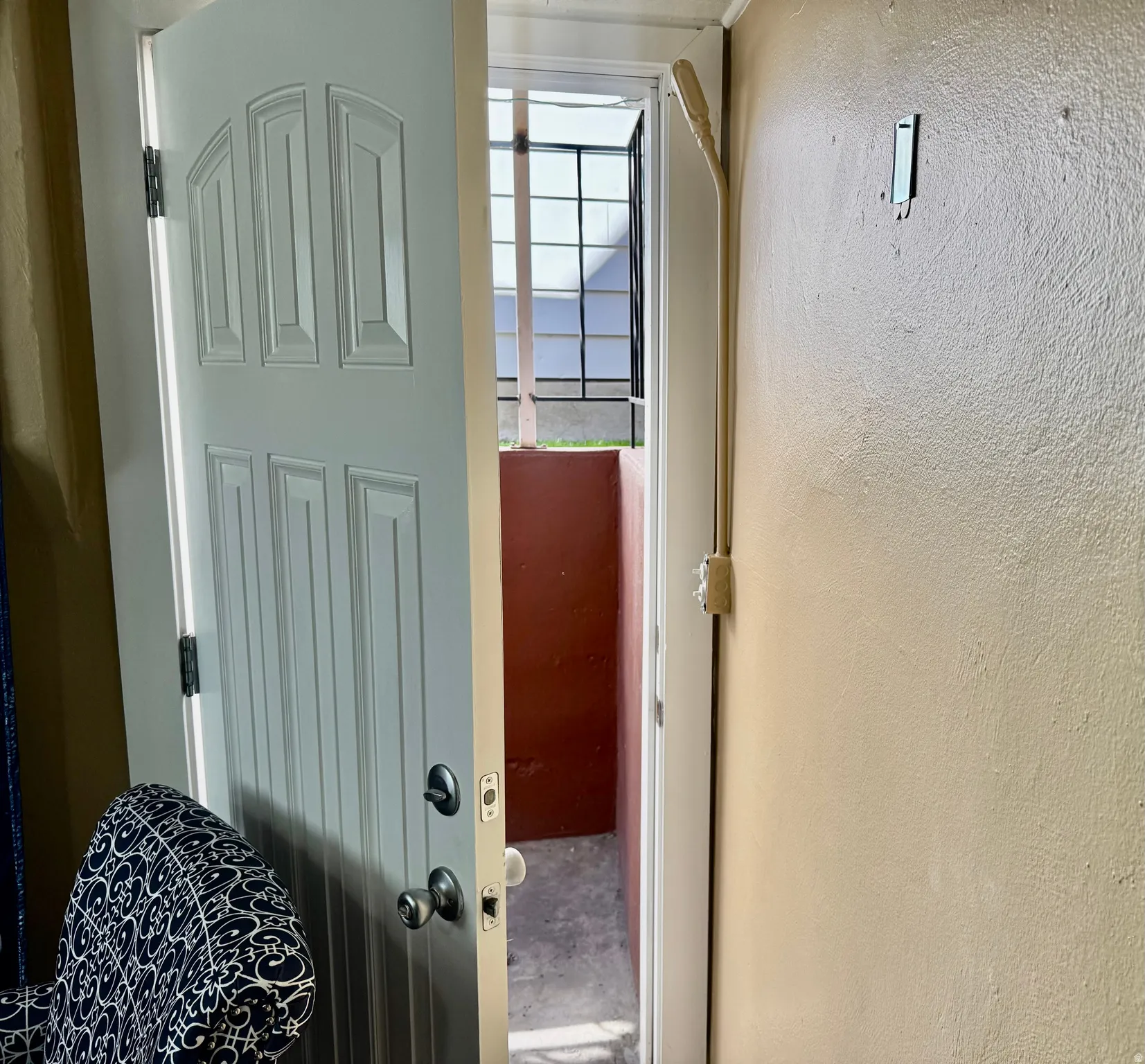 Doorway to outside with a textured wall and unfinished concrete flooring