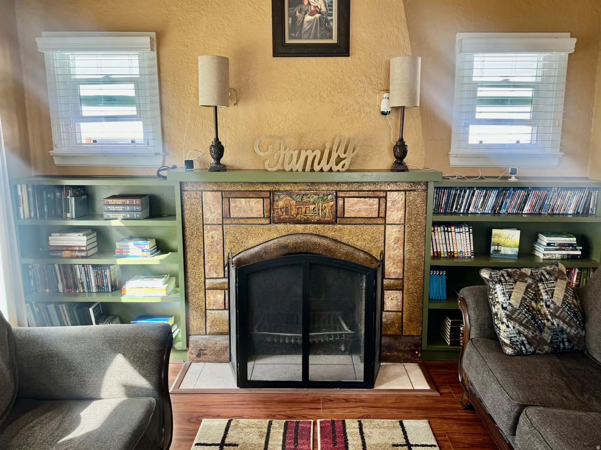 Sitting room with a textured wall, a tile fireplace, and wood finished floors