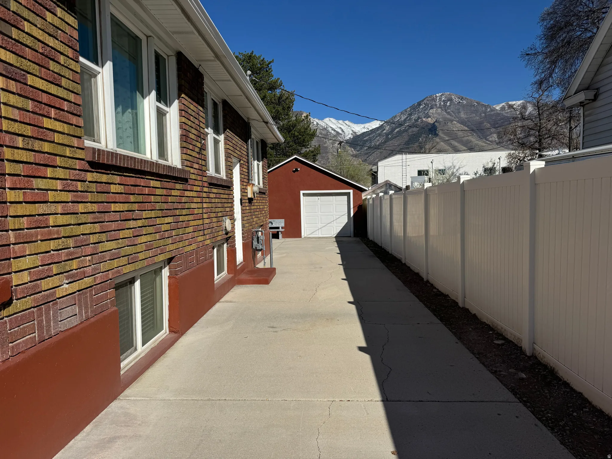 View of property exterior featuring brick siding, a garage, a mountain view, driveway, and an outbuilding