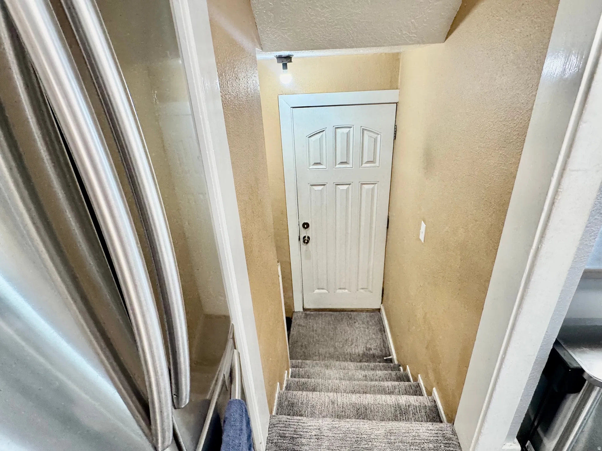 Stairway with a textured wall, a textured ceiling, and carpet