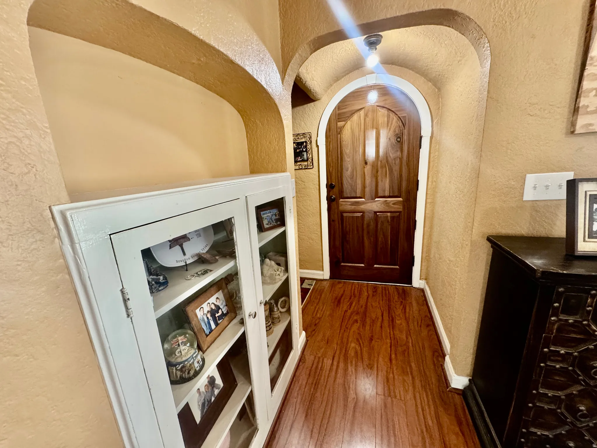Entrance foyer featuring a textured wall, arched walkways, and dark wood-style floors