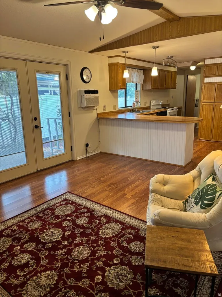 Kitchen featuring a peninsula, light wood-style flooring, decorative light fixtures, white electric range, and wood finish cabinets