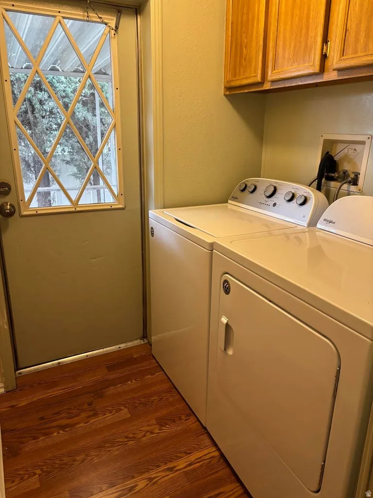 Laundry area with dark wood-style floors, cabinet space, independent washer and dryer, and a textured wall