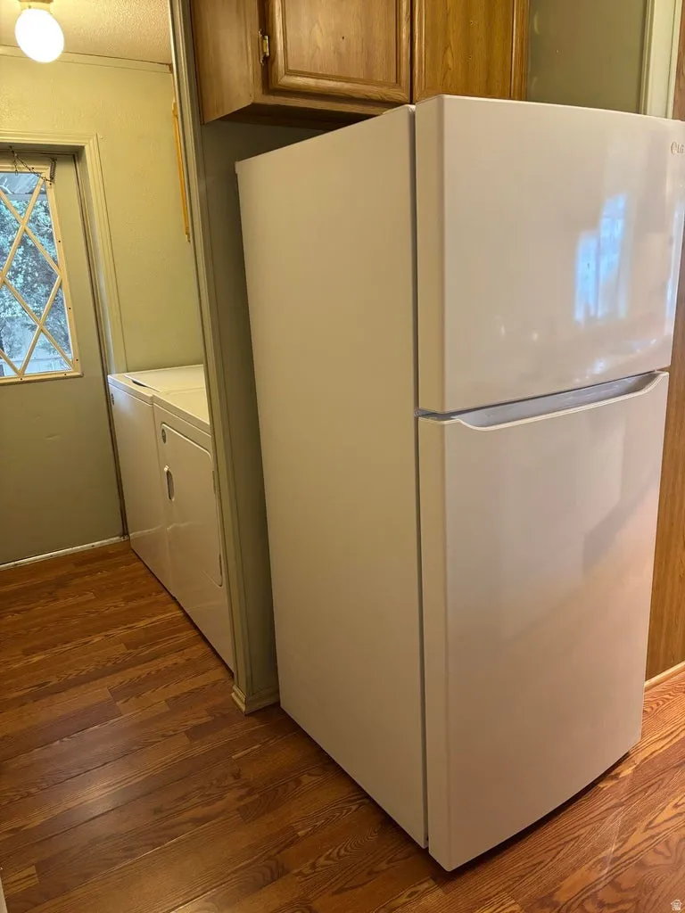 Laundry area featuring dark wood-type flooring and washing machine and clothes dryer