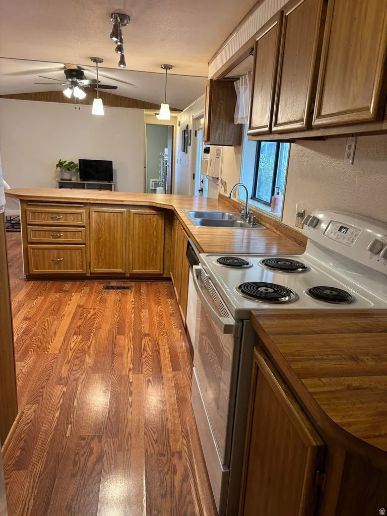 Kitchen featuring electric range, a peninsula, light wood-style flooring, light countertops.