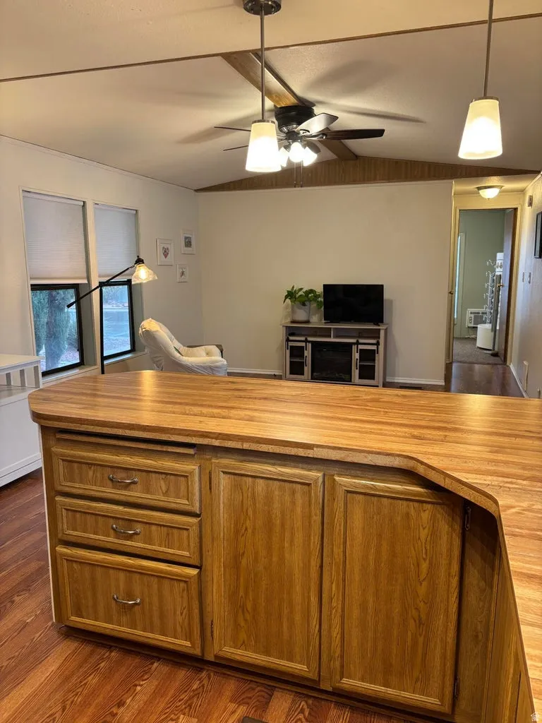 Kitchen featuring dark wood finished floors, ceiling fan, lofted ceiling, open floor plan.