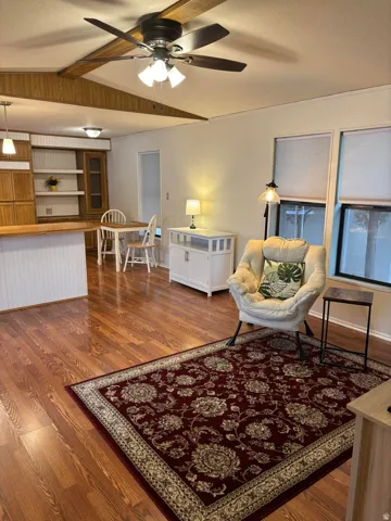 Living room with dark wood-type flooring, a ceiling fan.