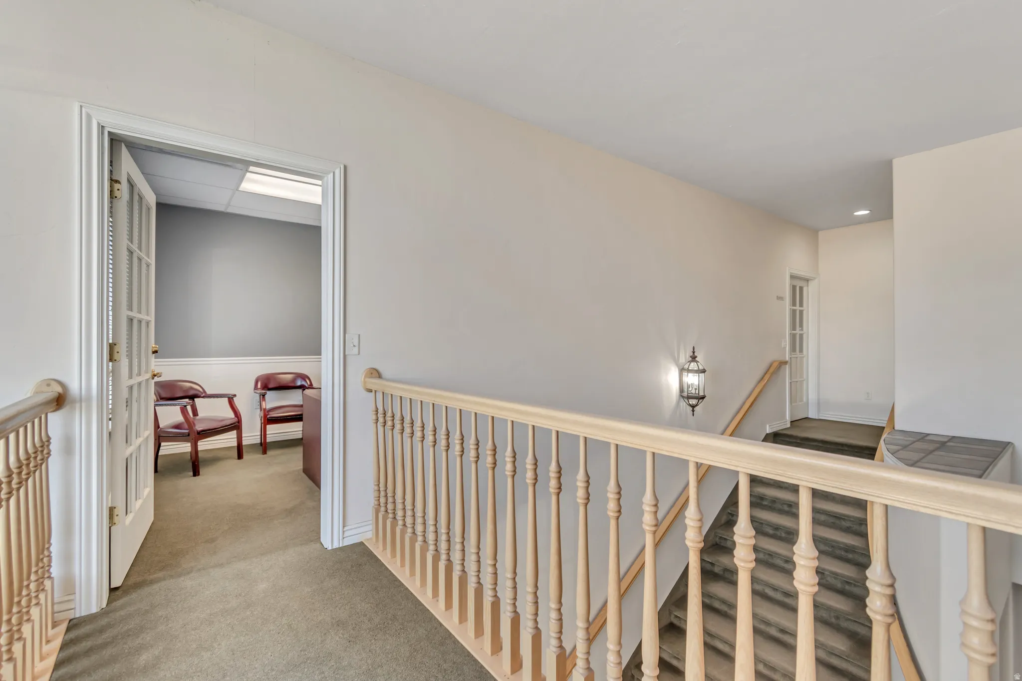 Hallway featuring an upstairs landing and light carpet