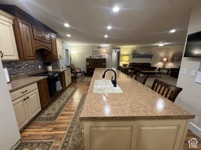 Kitchen with a breakfast bar, dark wood-type flooring, a large island, open floor plan, and black electric range oven
