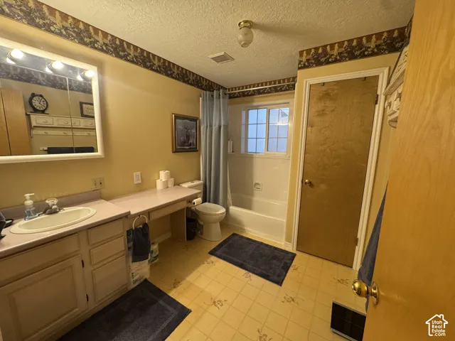 Bathroom with vanity, a textured ceiling, and shower / bathtub combination with curtain