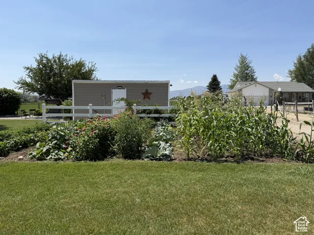 Expansive garden area featuring various plantings, white fencing, and a detached storage shed with vinyl siding