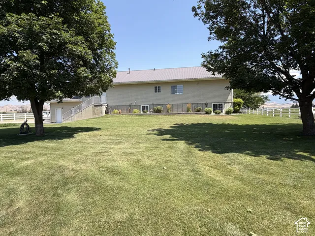 Expansive lawn with mature trees and a white fence border