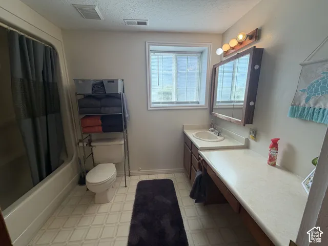 Bathroom featuring a vanity with a drop-in sink, an integrated countertop, wood-finish cabinetry, and a framed mirror with overhead lighting