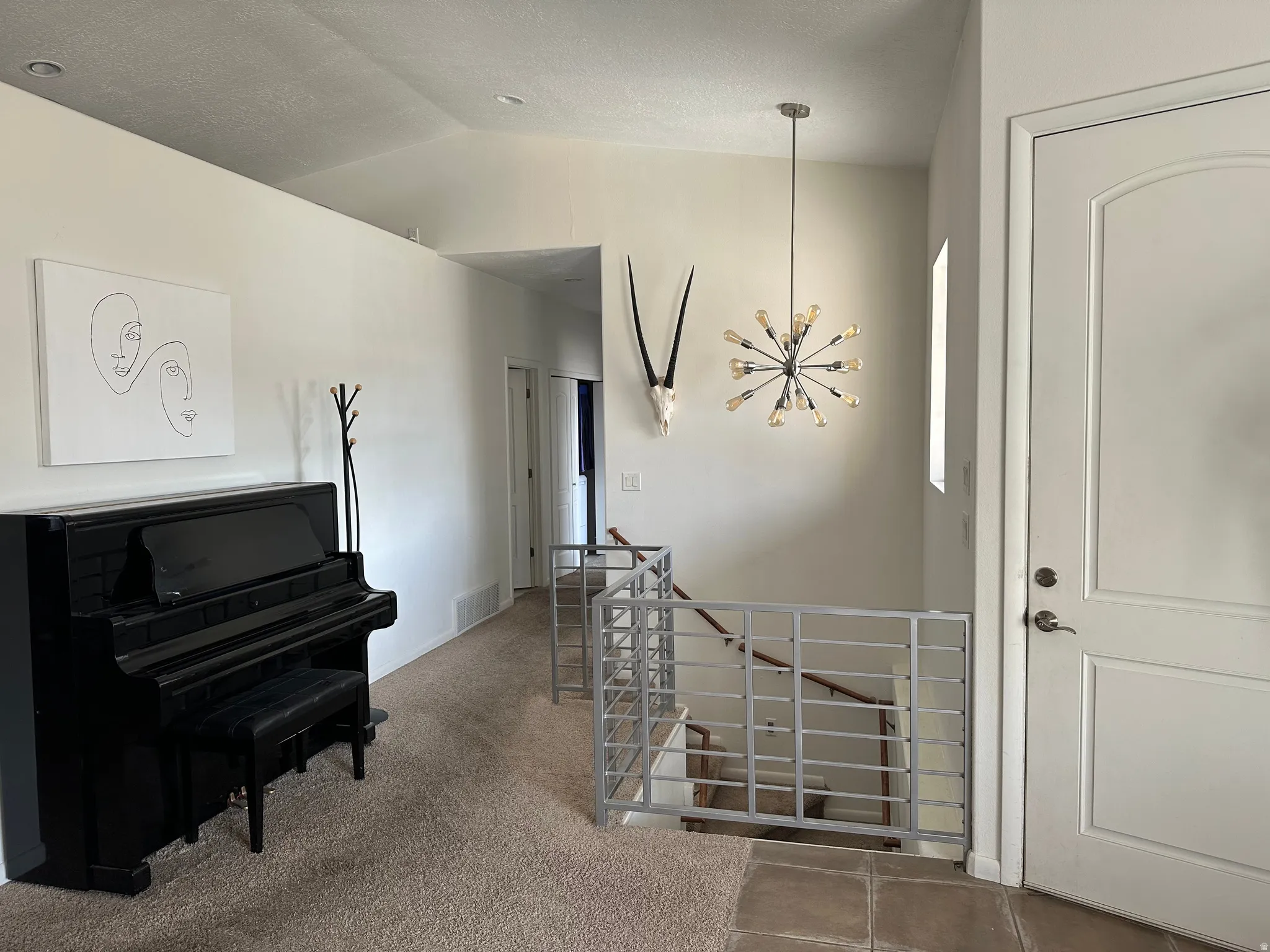 Entryway with lofted ceiling, light colored carpet, and hanging lights