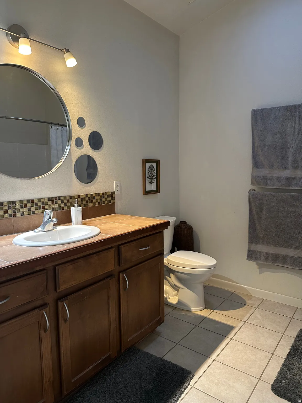 Full bathroom featuring vanity, light tile patterned floors, backsplash, and a shower with curtain