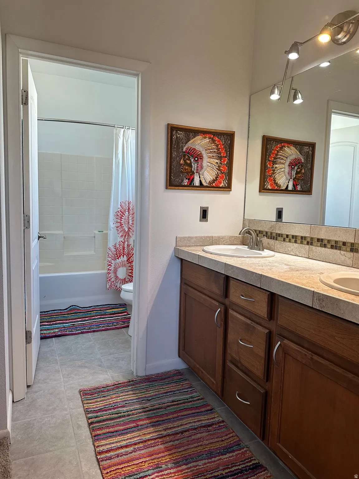 Bathroom featuring double vanity, shower / bath combination with curtain, and light tile patterned floors