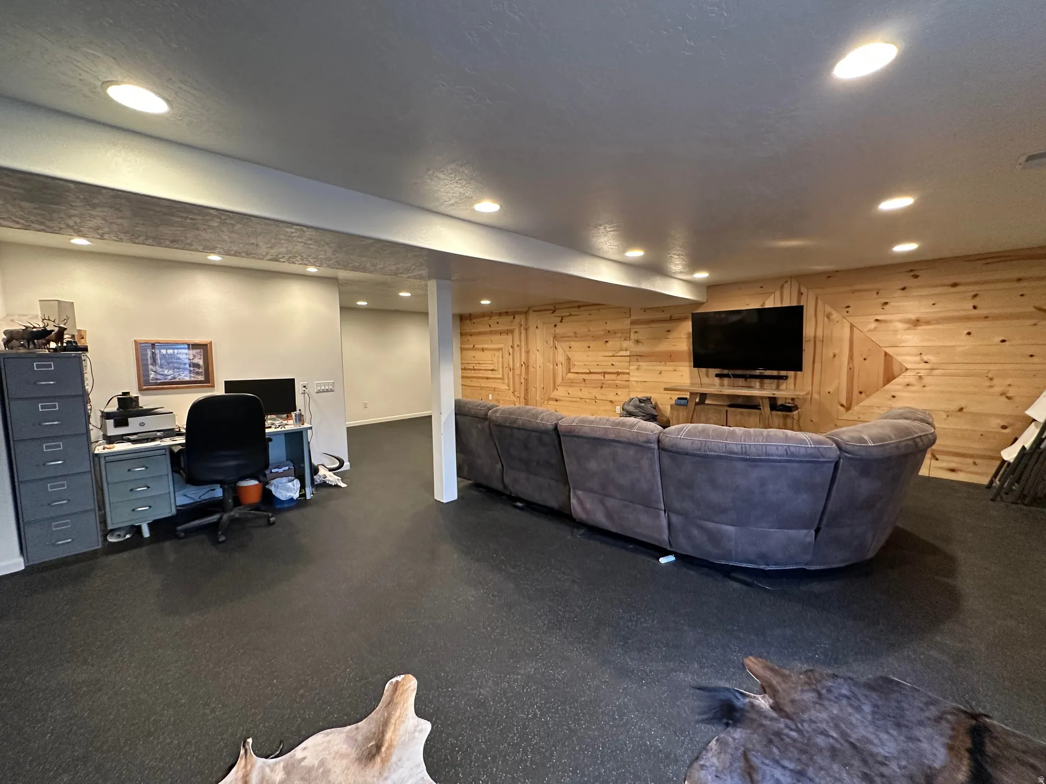 Living area with wood walls, a desk, and recessed lighting