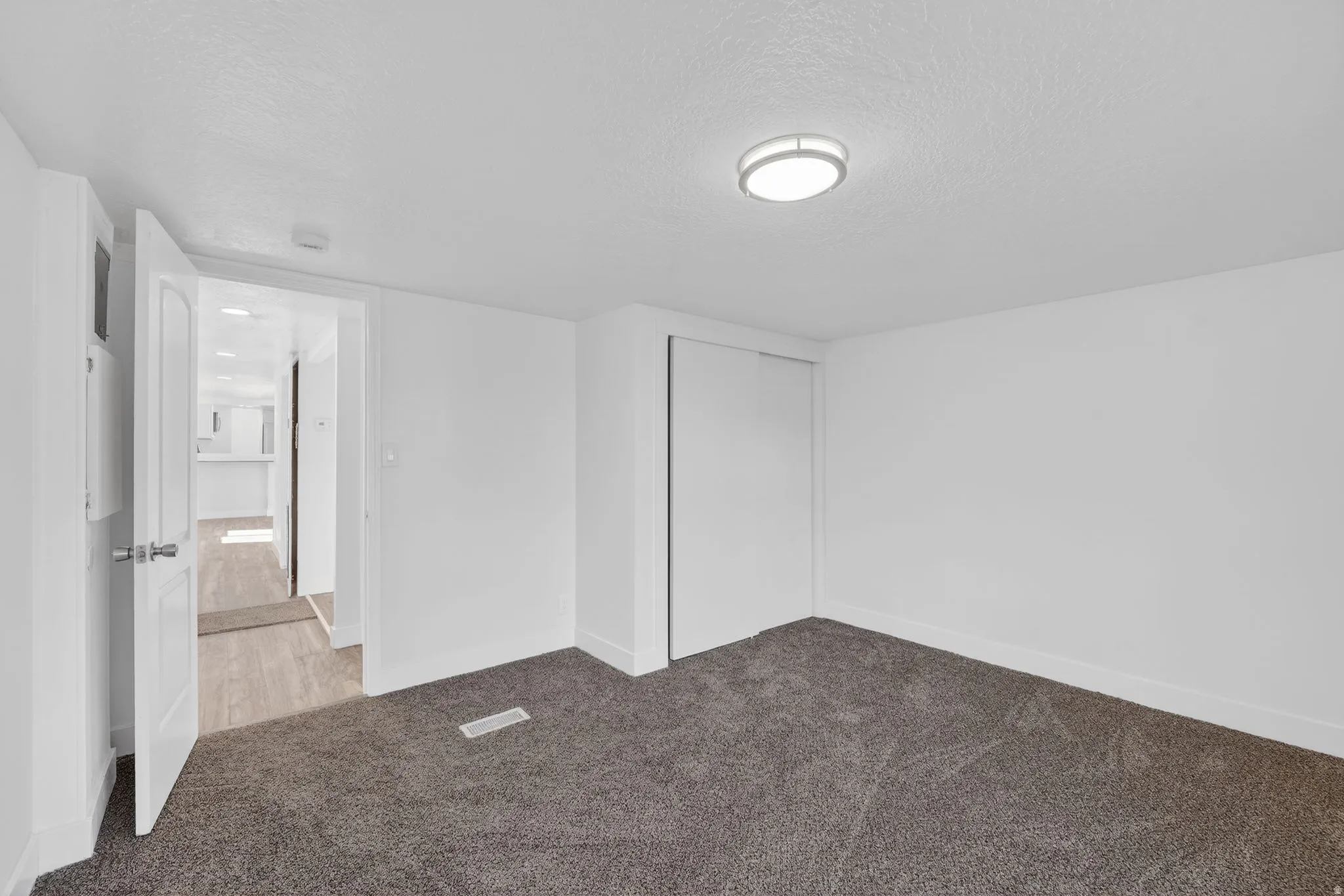 Unfurnished bedroom featuring light carpet, a closet, and a textured ceiling