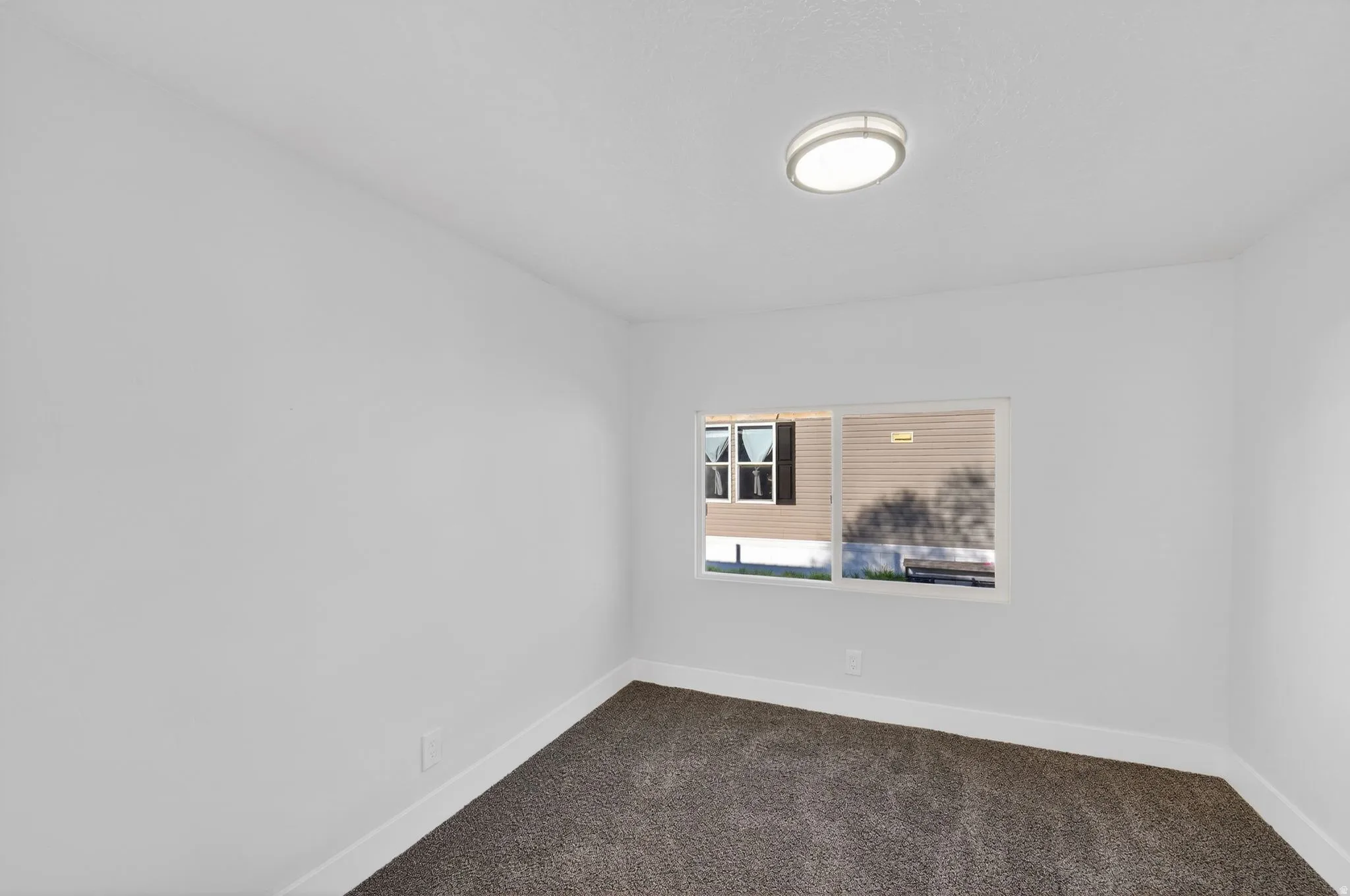 Spare room featuring dark carpet and baseboards