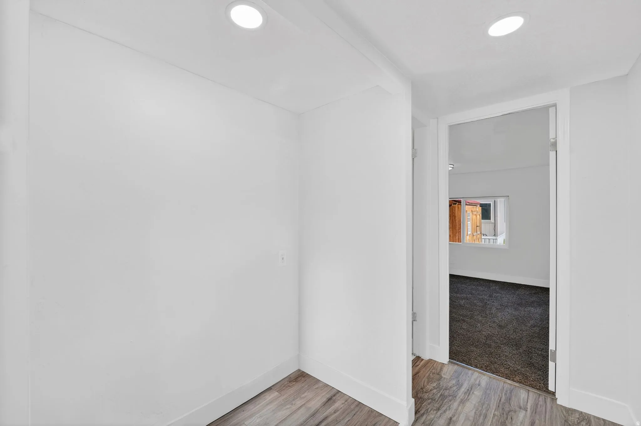 Corridor with light wood-type flooring and recessed lighting