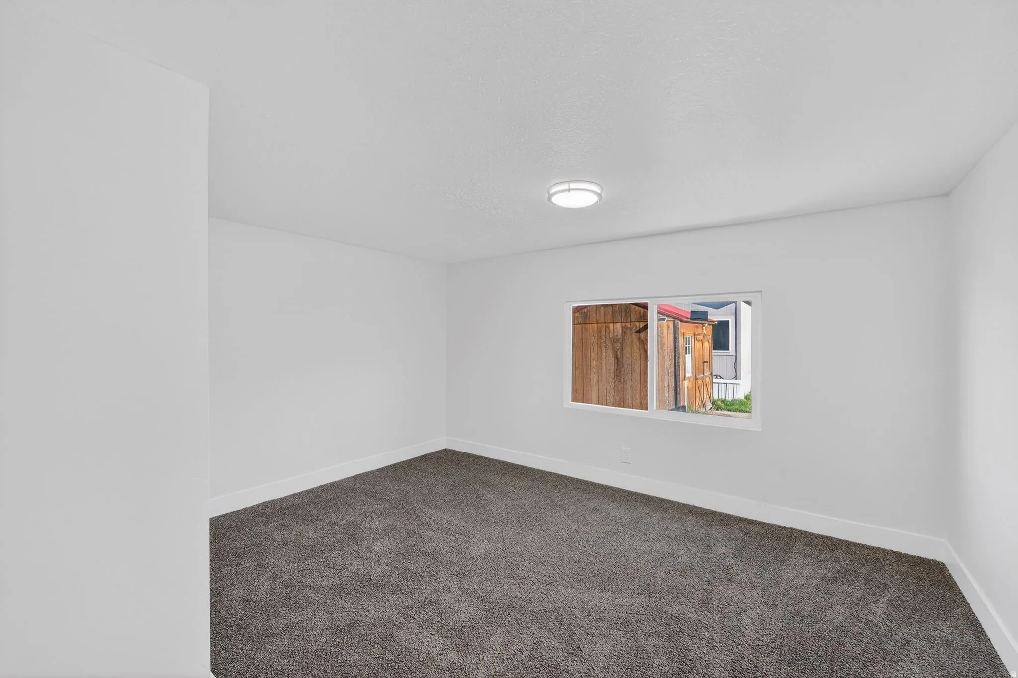 Spare room featuring baseboards and dark colored carpet