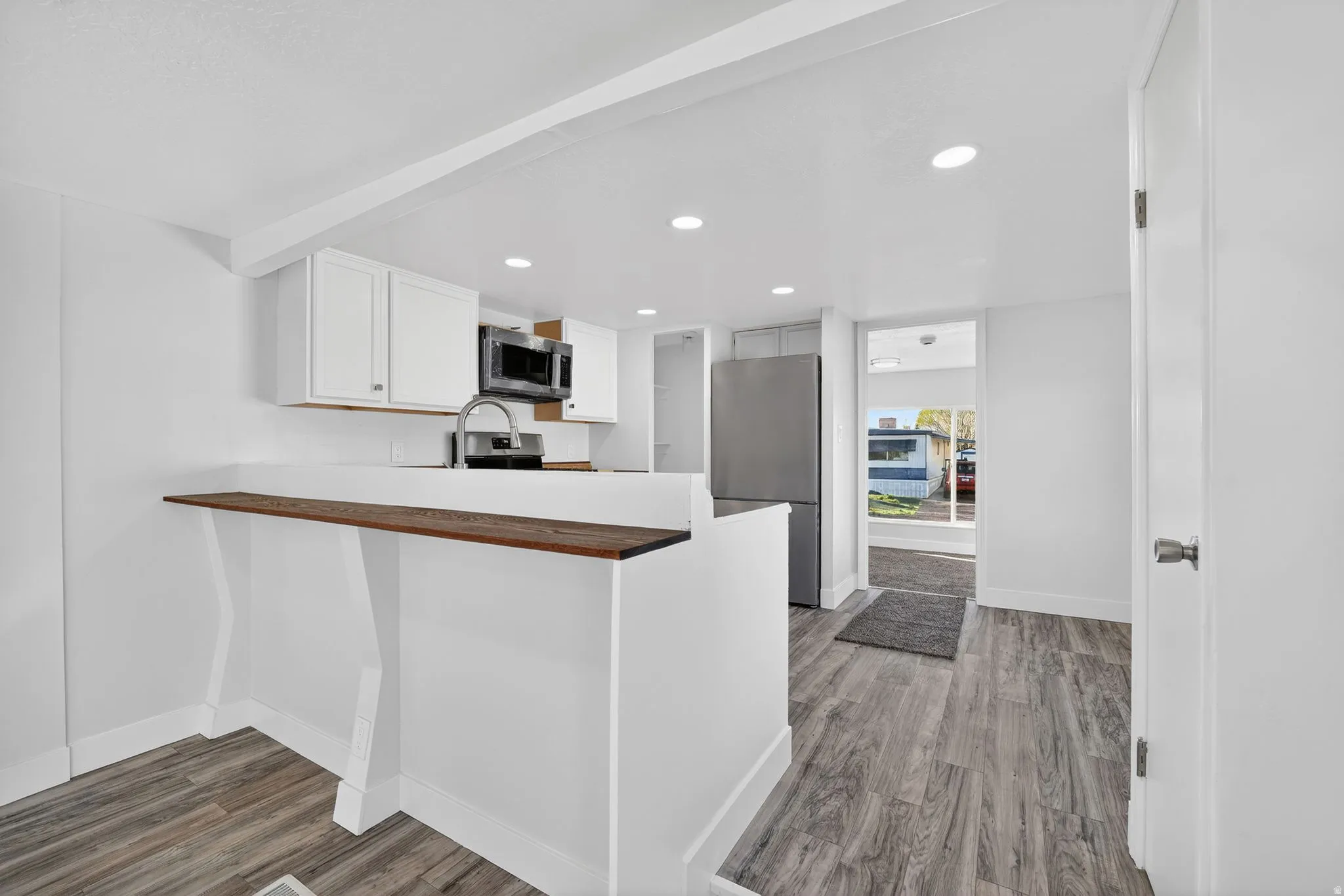 UPDATED Kitchen with  new stainless steel appliances, light wood-style floors, a peninsula, recessed lighting, and white cabinets
