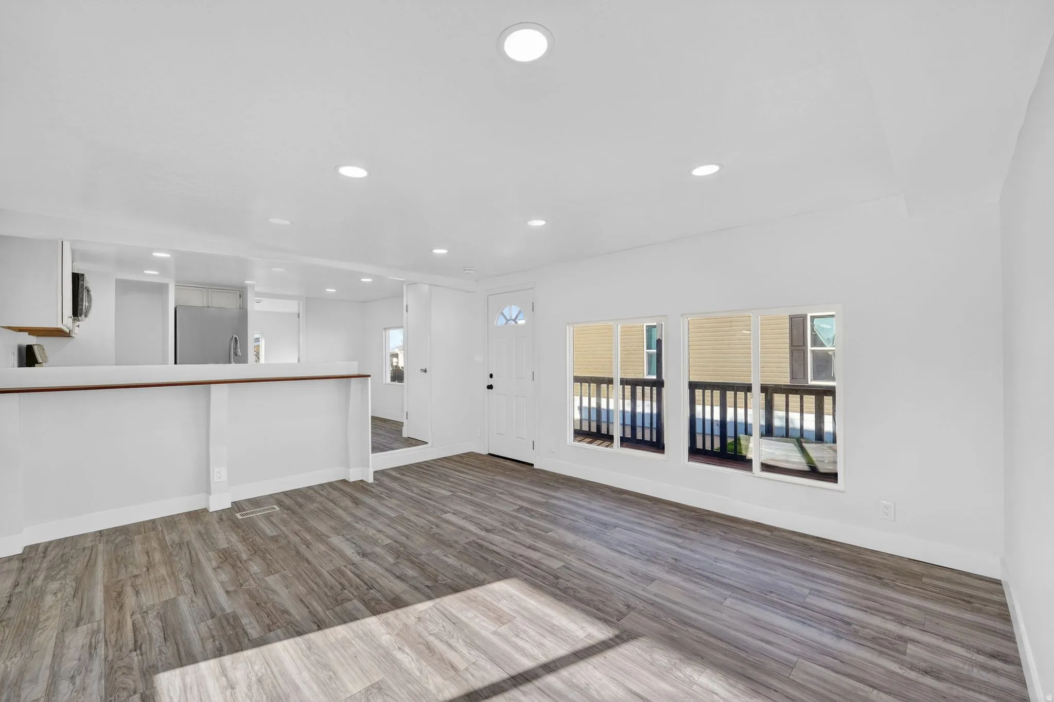 Unfurnished living room featuring dark wood finished floors, recessed lighting, and plenty of natural light