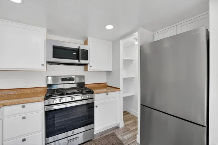 Kitchen featuring stainless steel appliances, light countertops, white cabinets, and recessed lighting