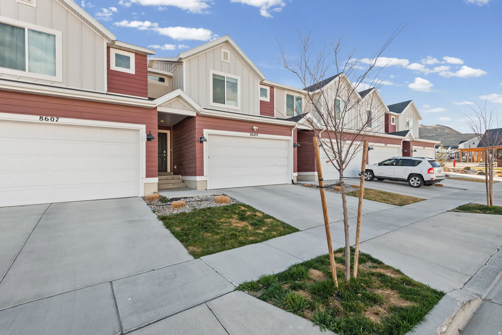 View of front facade featuring board and batten siding, driveway, an attached garage, and a residential view
