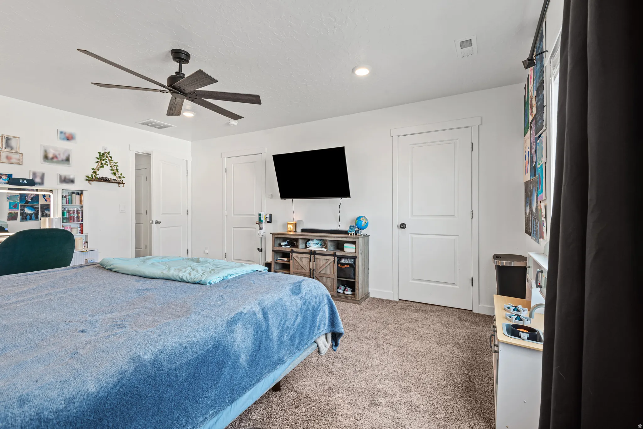 Bedroom with a ceiling fan, light colored carpet, and a textured ceiling