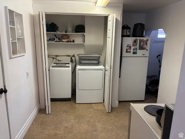 Laundry area with washer and clothes dryer and light floors