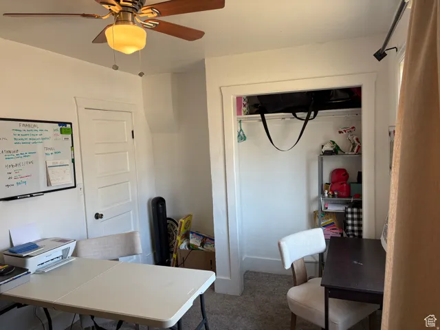 Office space featuring ceiling fan and dark carpet