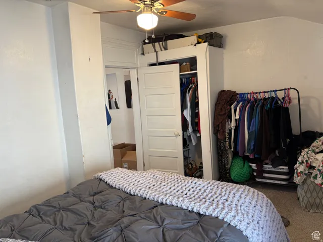 Carpeted bedroom featuring a closet, ceiling fan, and vaulted ceiling
