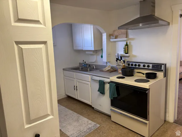 Kitchen with white appliances, arched walkways, white cabinets, light countertops, and open shelves
