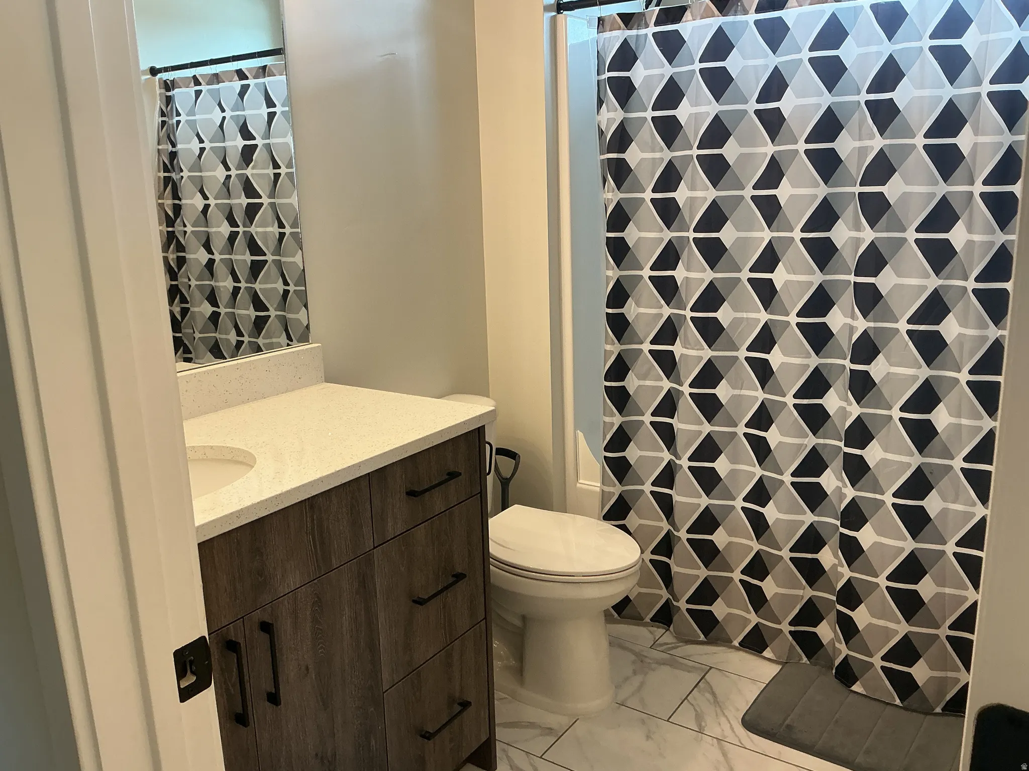 Full bath featuring vanity, a shower with curtain, and light marble finish floors