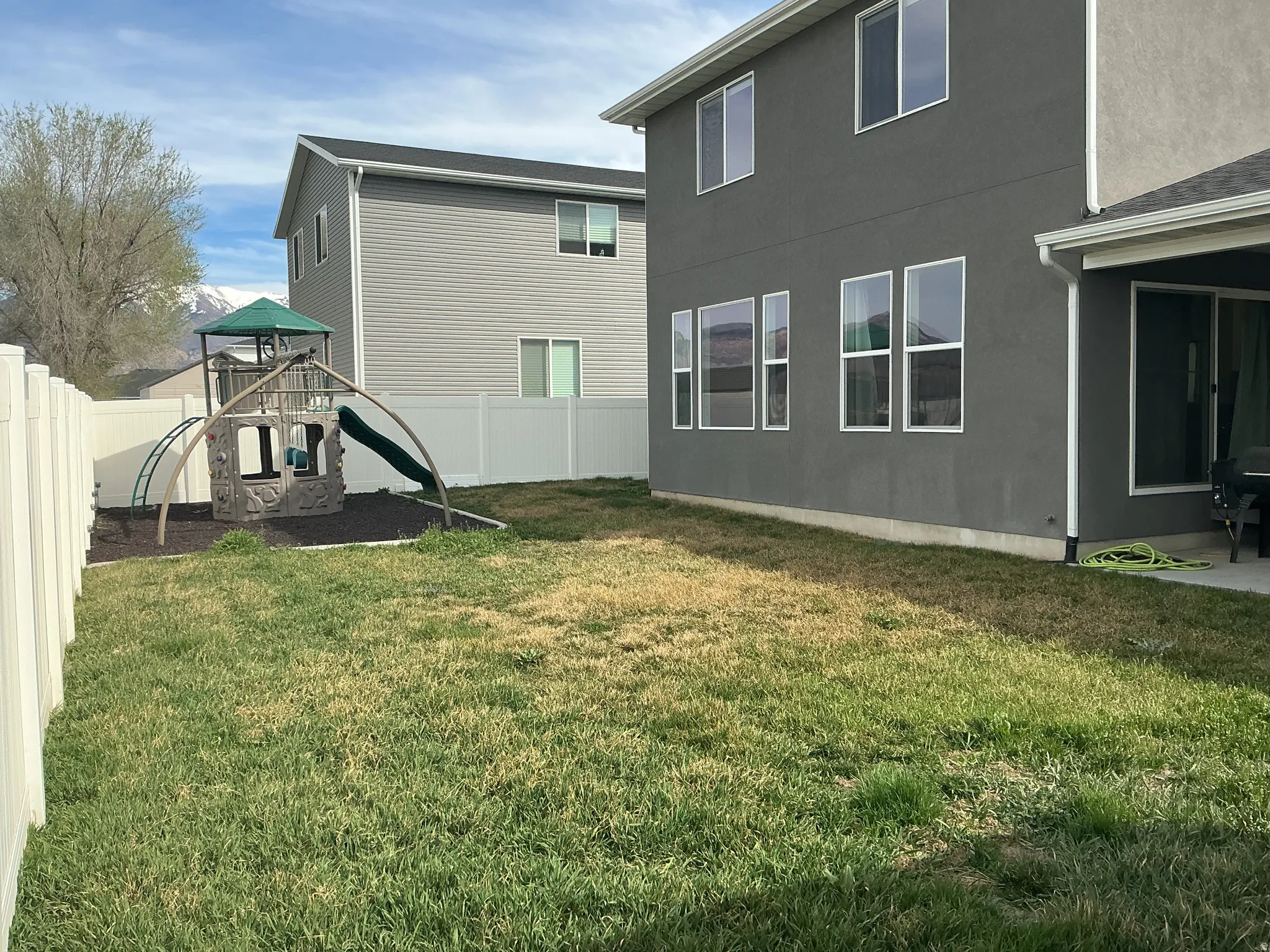 Rear view of house with a playground, stucco siding, and a fenced backyard