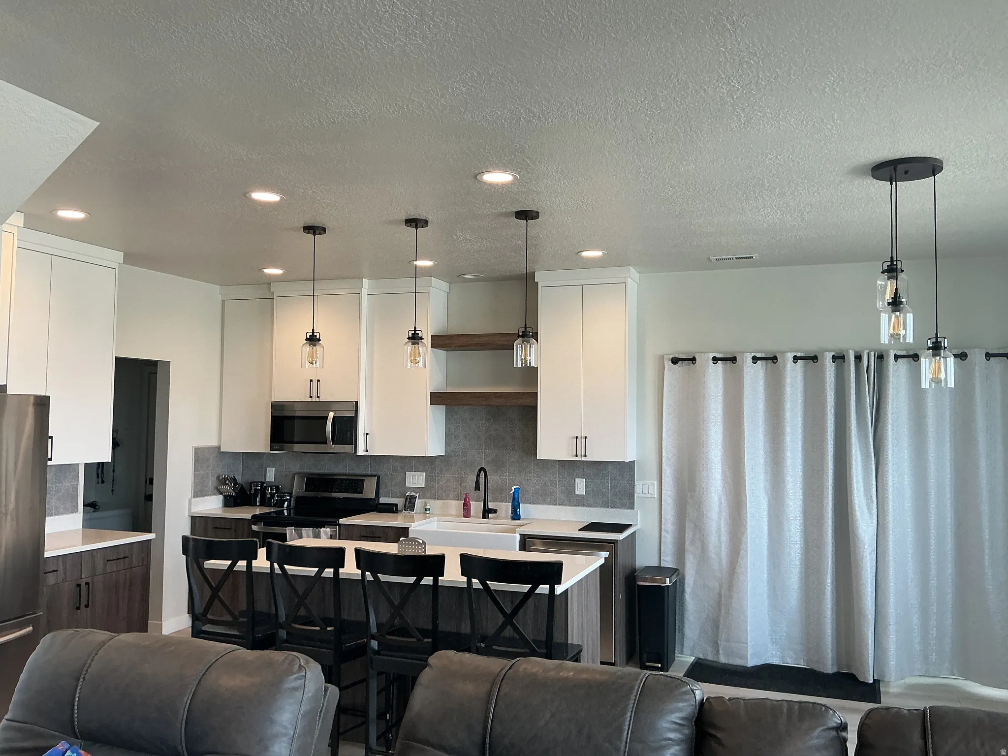 Dual tone kitchen featuring a breakfast bar, open floor plan, stainless steel appliances, dual tone cabinets, and an island with sink