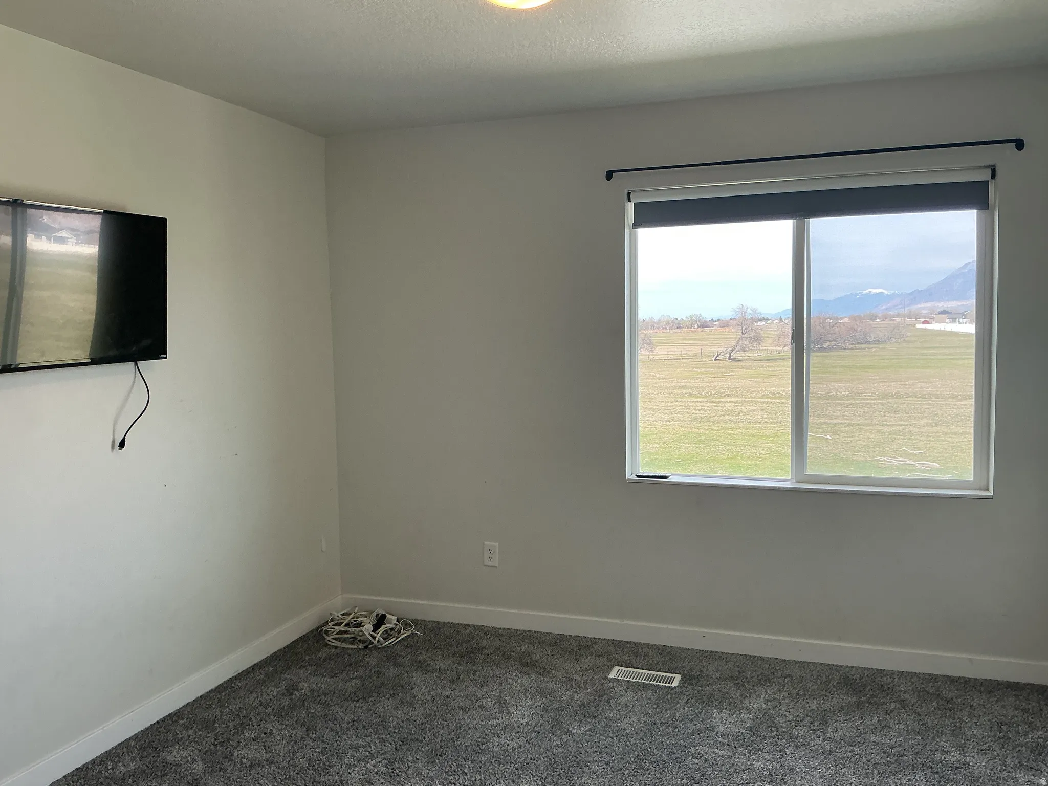 Empty room with dark carpet, a mountain view, and a textured ceiling