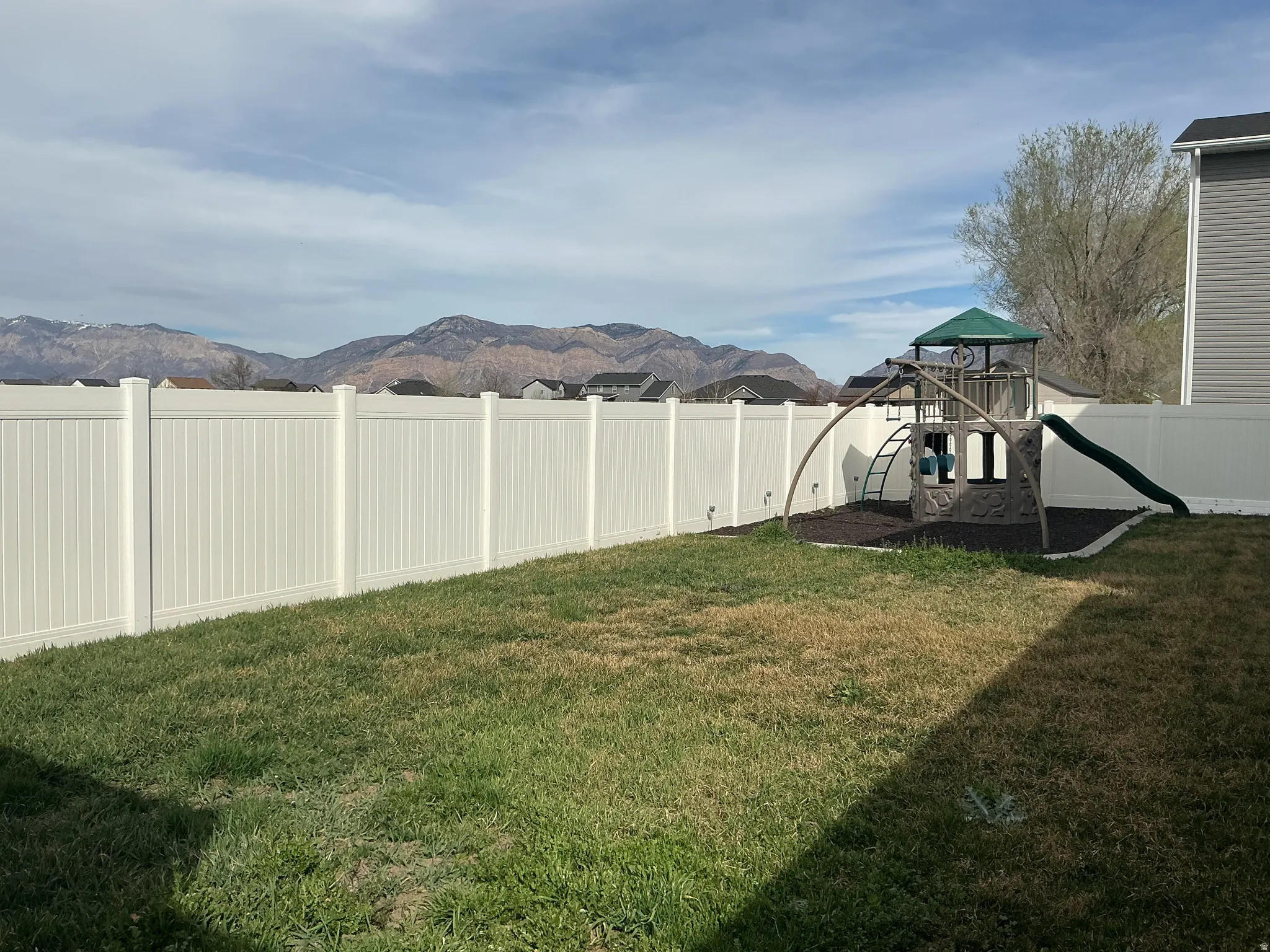 Fenced backyard featuring a playground and a mountain view