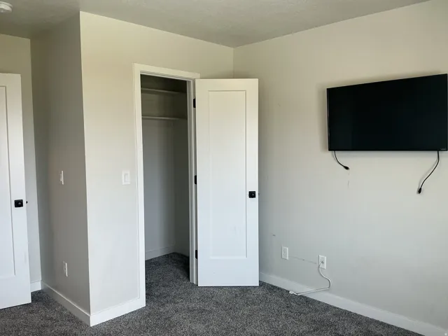 Unfurnished bedroom with dark colored carpet and a spacious closet